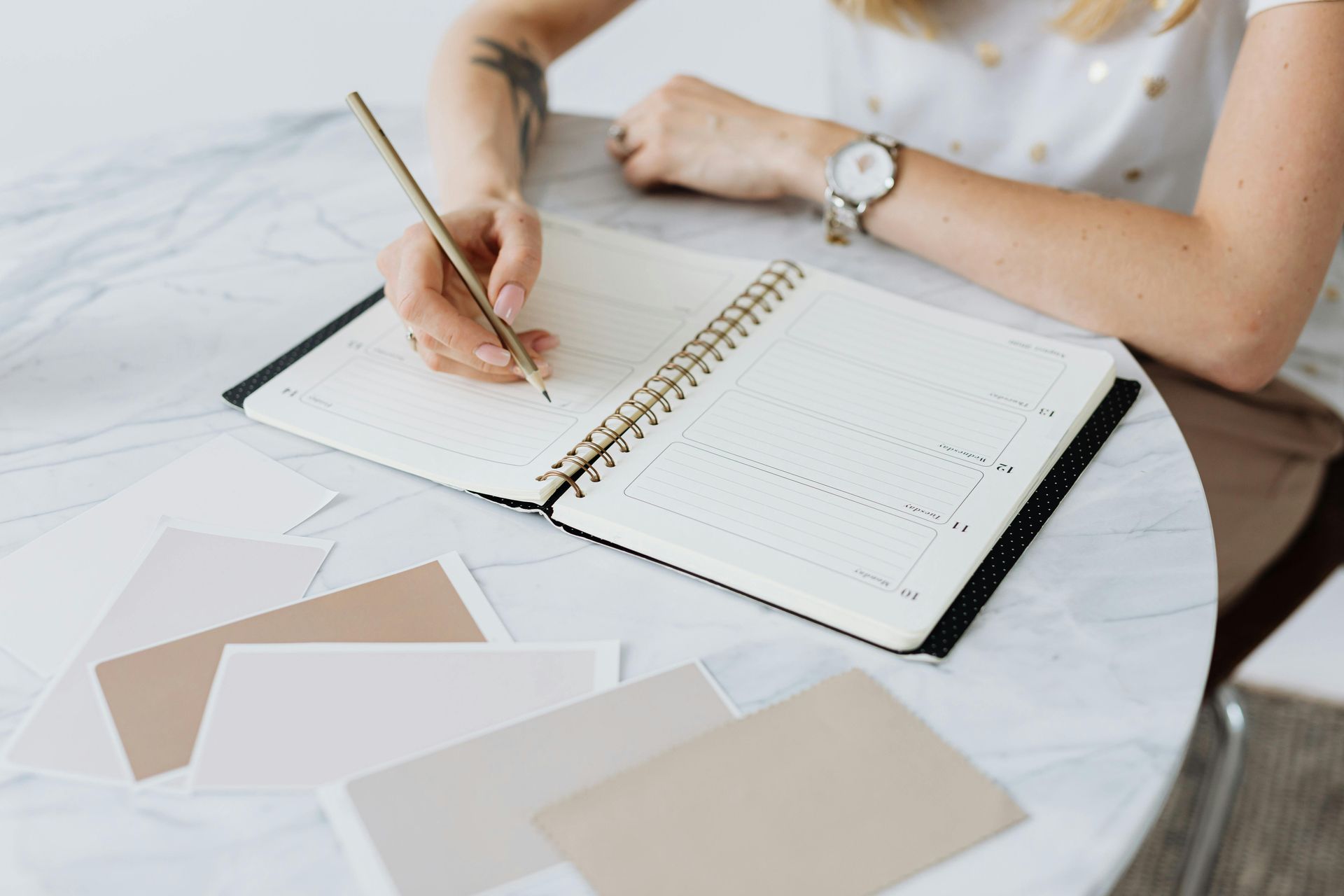 A person is writing in a notebook with a pencil