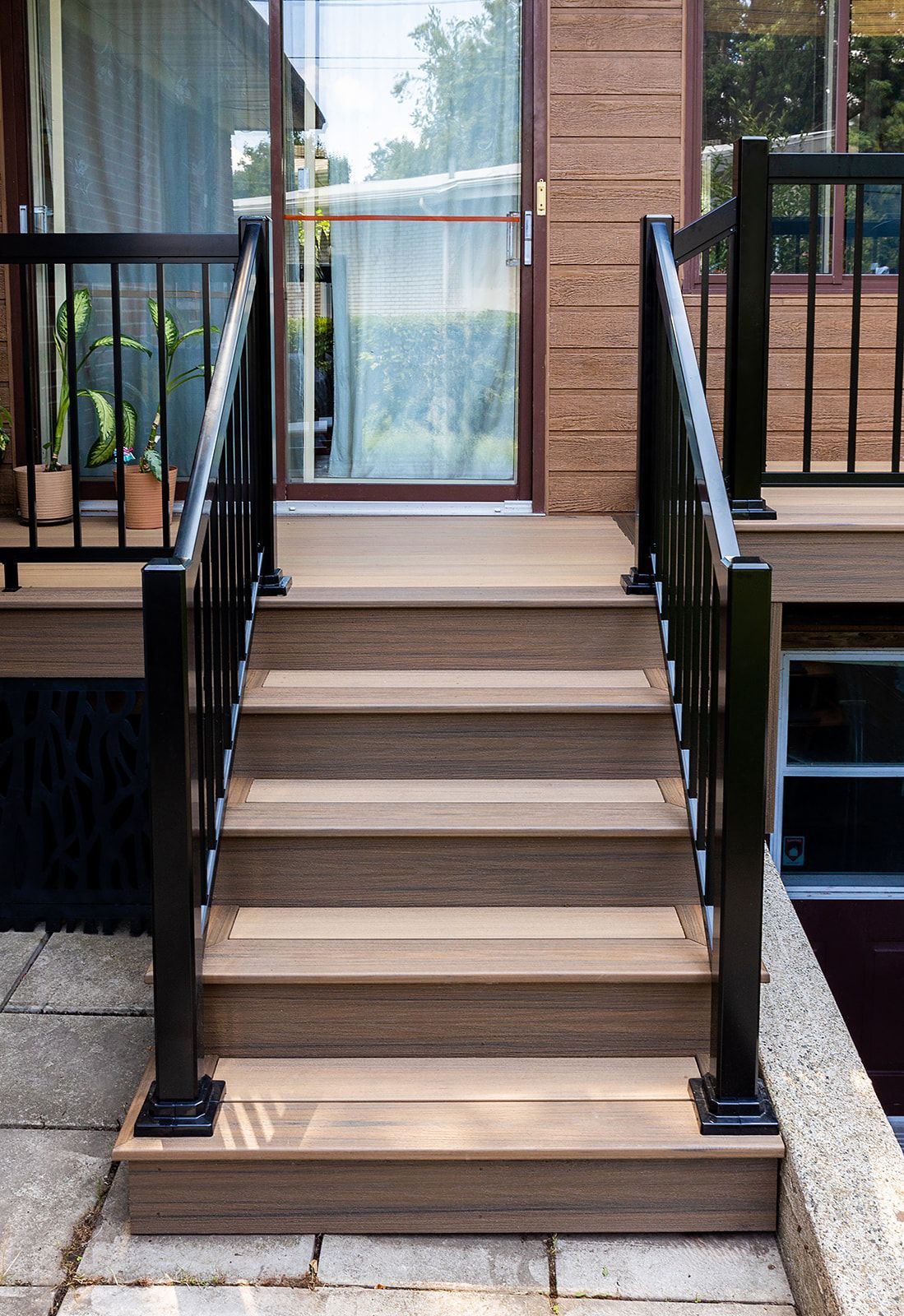 Un escalier en bois avec une rampe noire mène à une porte.