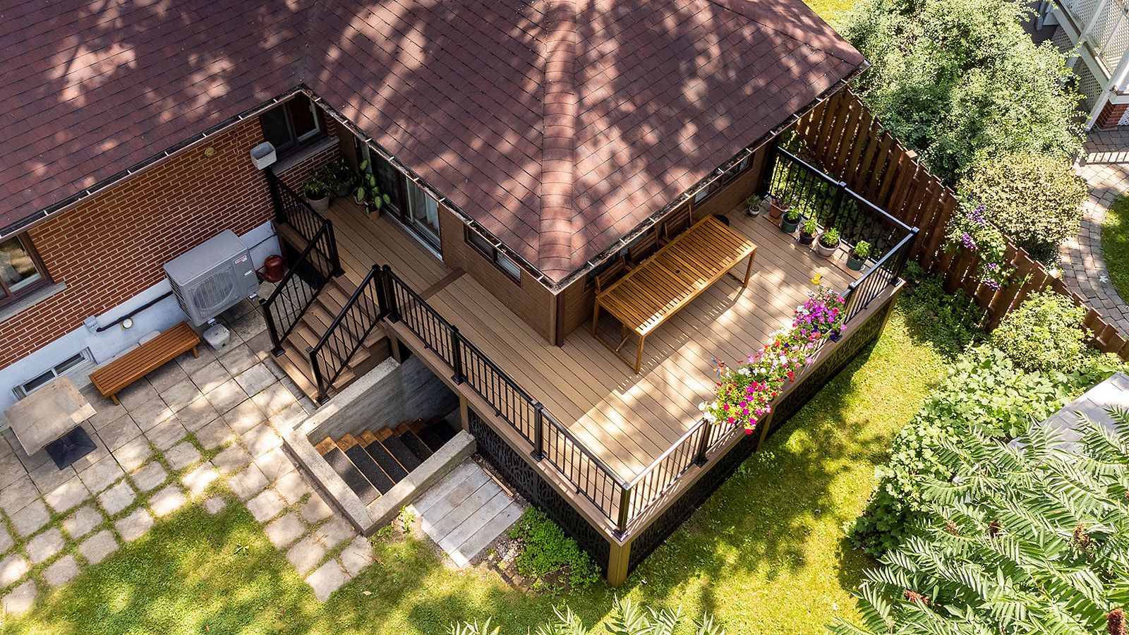 Terrasse en bois avec toit marron, rambarde et mobilier de jardin, entourée de verdure.