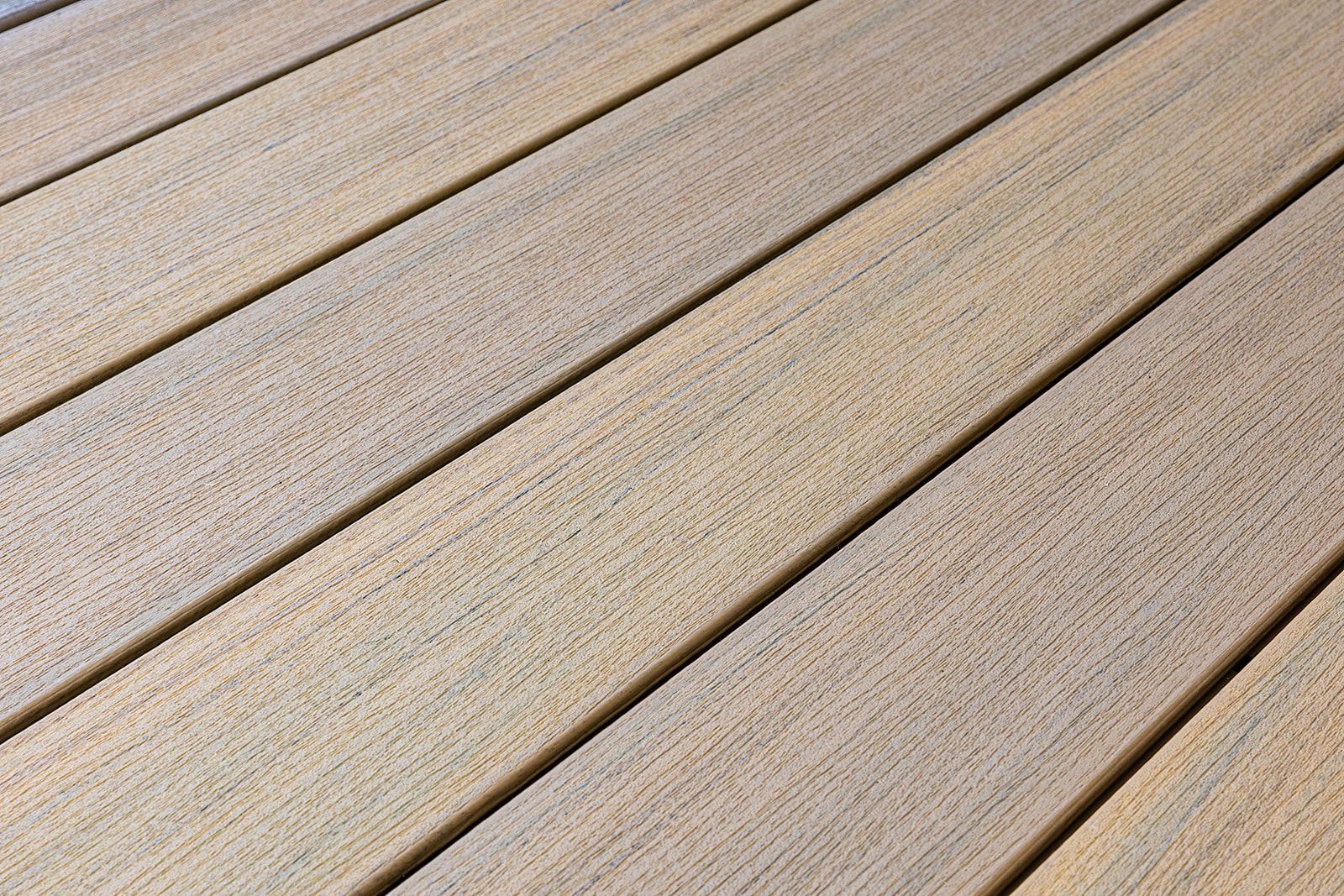 Gros plan sur des planches de bois posées en diagonale, présentant une surface rugueuse et texturée, et des rainures entre elles.