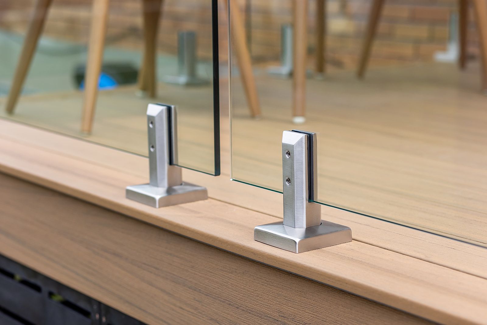 Garde-corps en panneaux de verre avec supports en métal argenté sur une terrasse en bois.