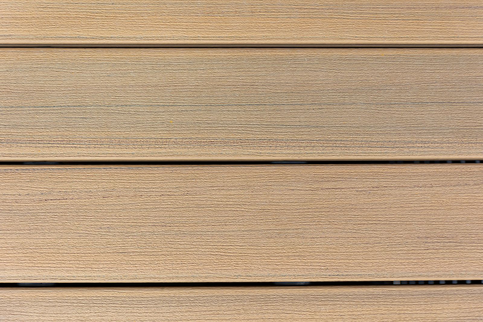 Gros plan sur quatre lames de terrasse horizontales, texturées, en composite brun clair, avec des lignes sombres entre elles.
