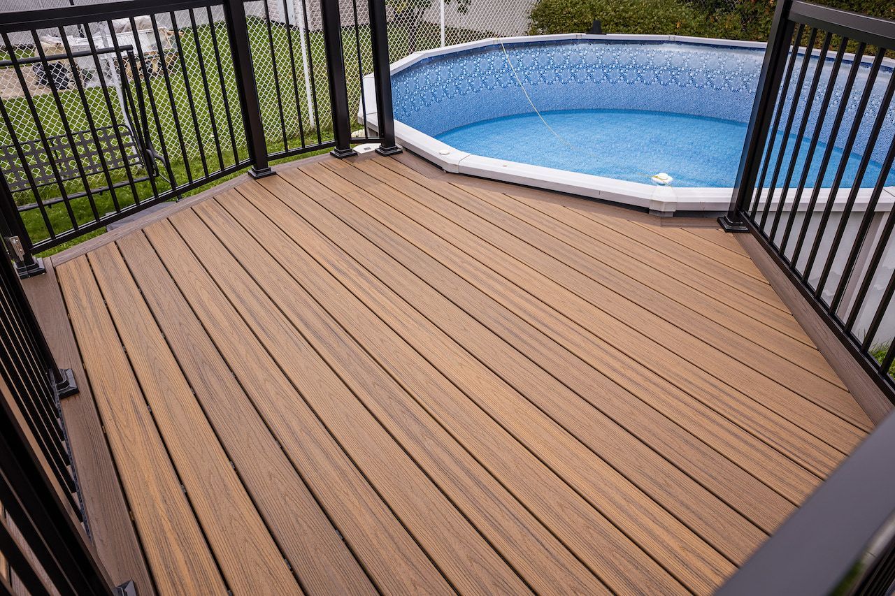 Terrasse en bois avec rambarde noire donnant sur une piscine hors sol bleue.