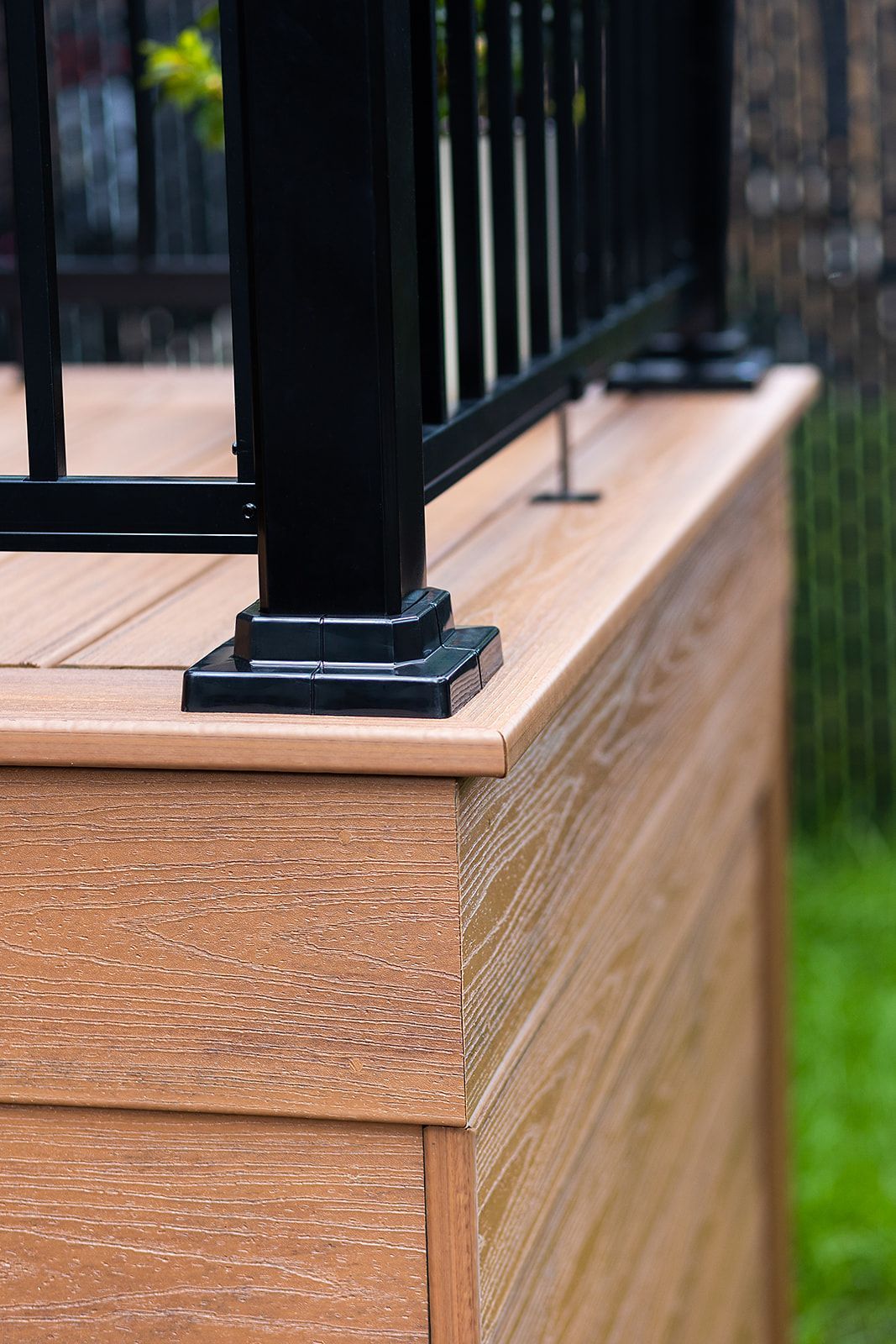 Gros plan sur une terrasse en composite marron avec une rambarde noire.