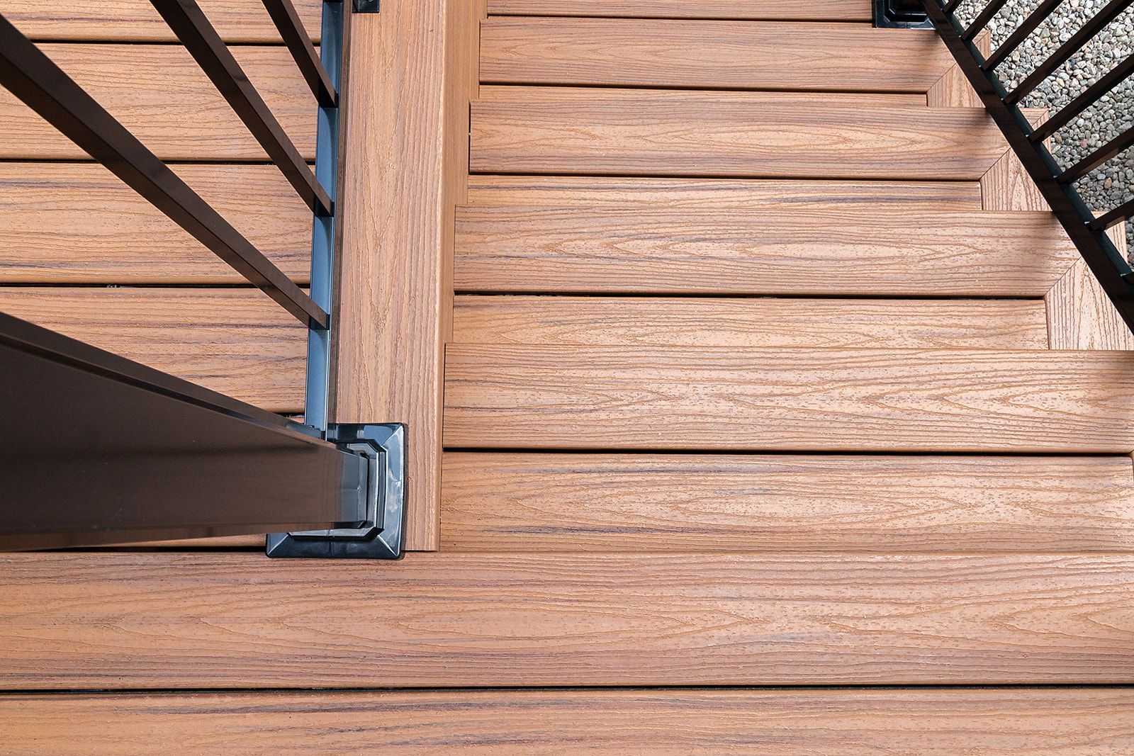 Escalier en bois avec une rampe en métal noir et une terrasse marron.