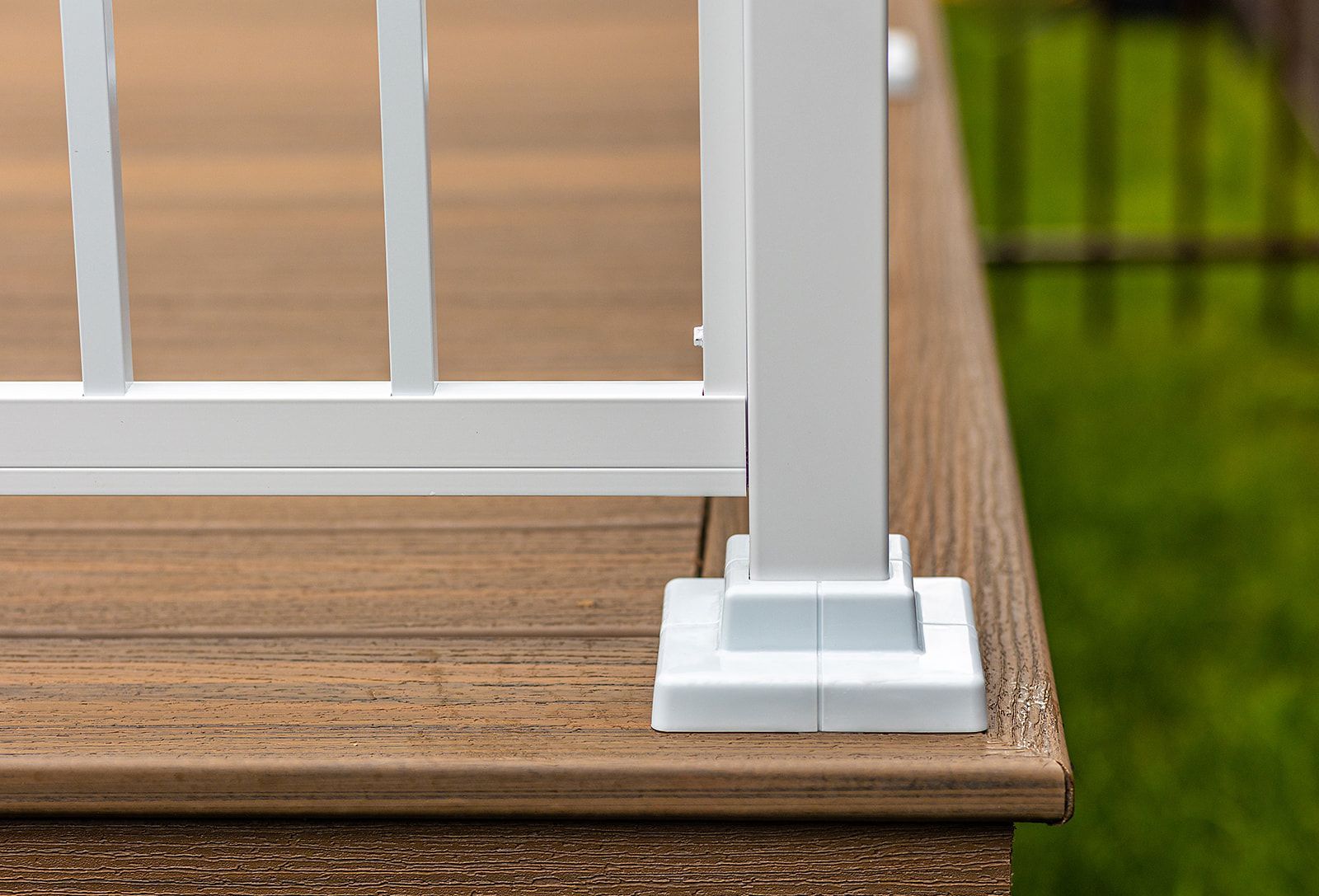 Poteau de rambarde blanc sur lames de terrasse composites brunes.