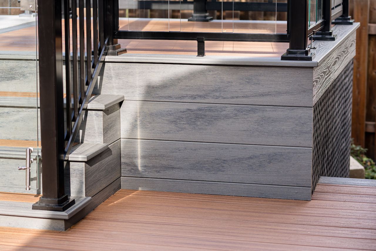 Terrasse avec bardage composite gris et rambarde noire.