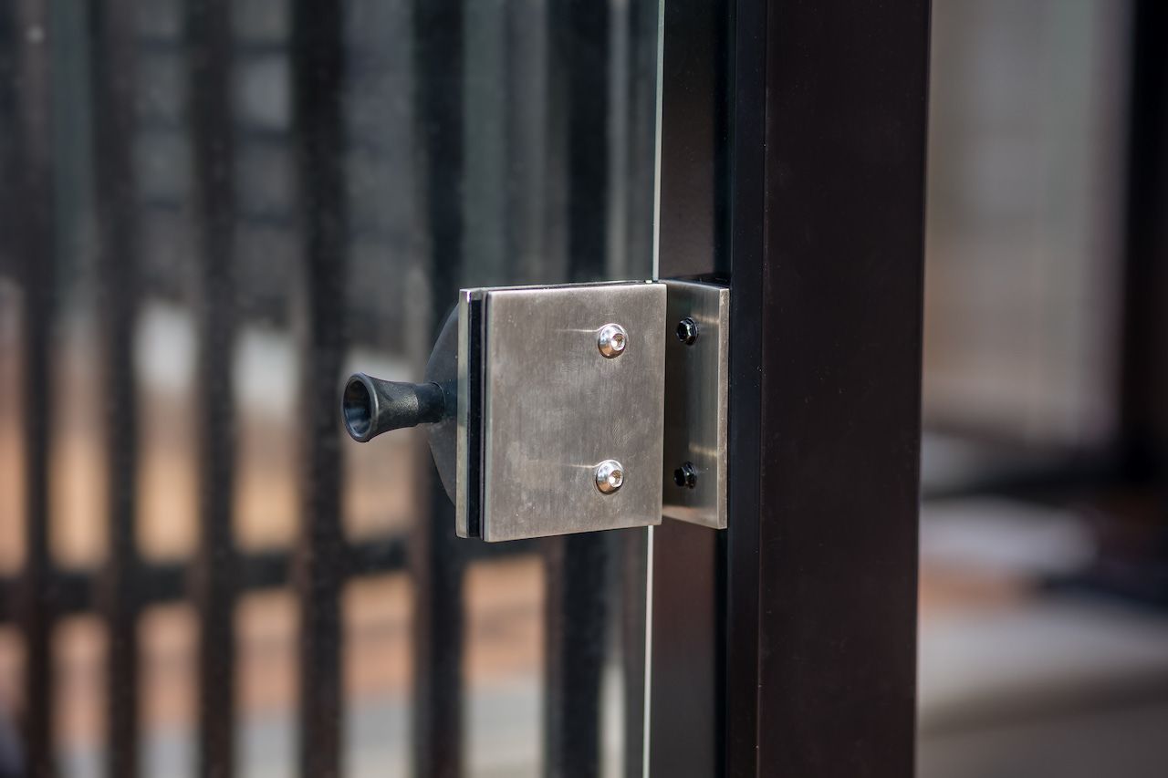 Loquet de porte en métal sur un cadre de porte en verre, couleur foncée.