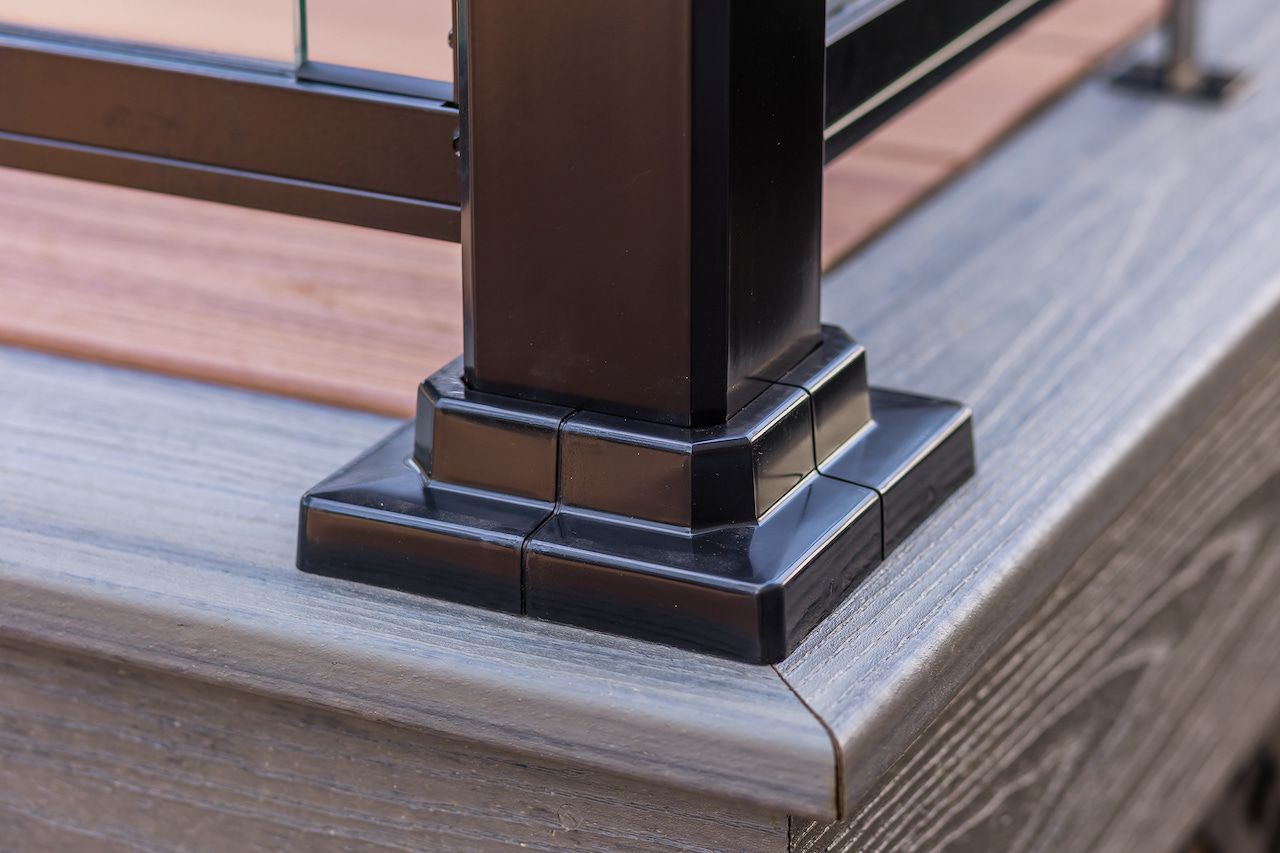 Socle de poteau de terrasse noir avec détails décoratifs, monté sur une terrasse en composite gris.