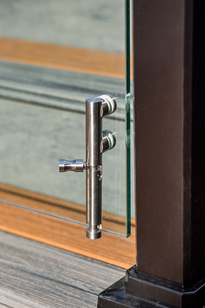Poignée de porte en acier inoxydable fixée à un panneau de verre.