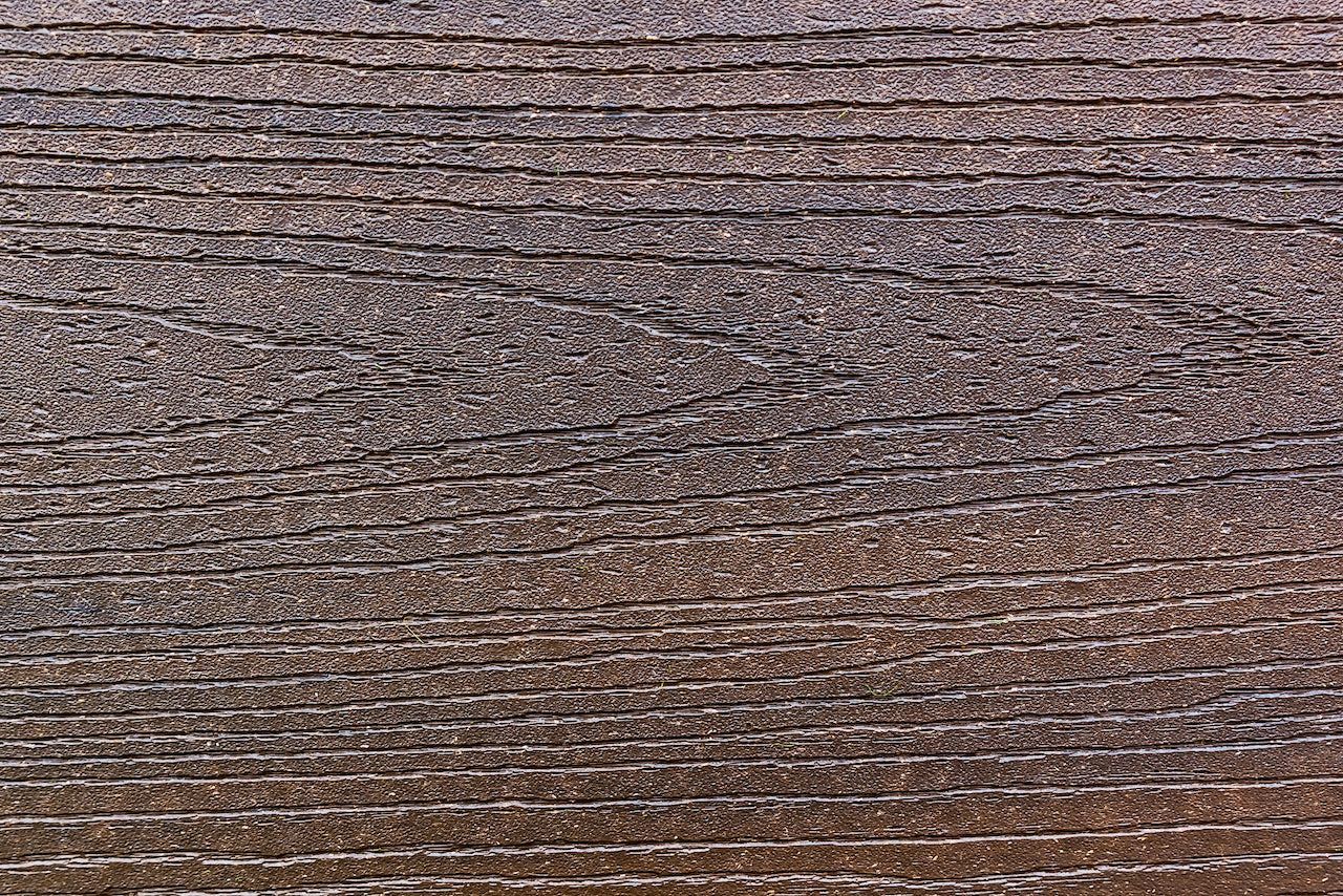 Gros plan sur des planches de bois patinées par le temps, présentant des rainures horizontales et une surface texturée, et montrant des variations de tons bruns et gris.