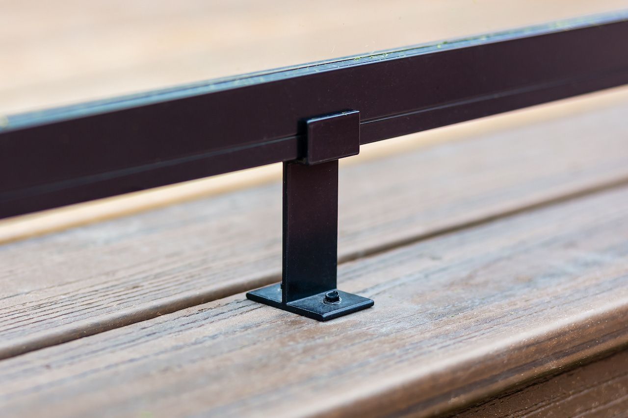 Poteau de rambarde en métal noir fixé à une terrasse en bois.