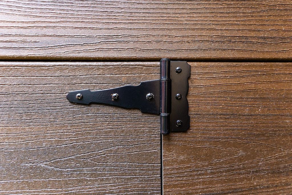Charnière en T en métal noir sur planches de bois.