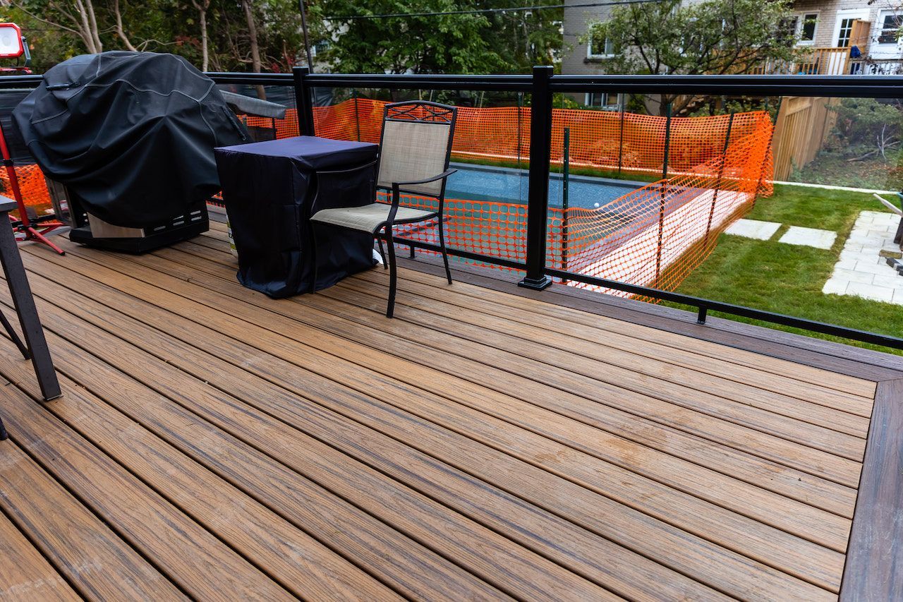 Terrasse en bois avec mobilier de jardin, donnant sur une petite piscine et un jardin.