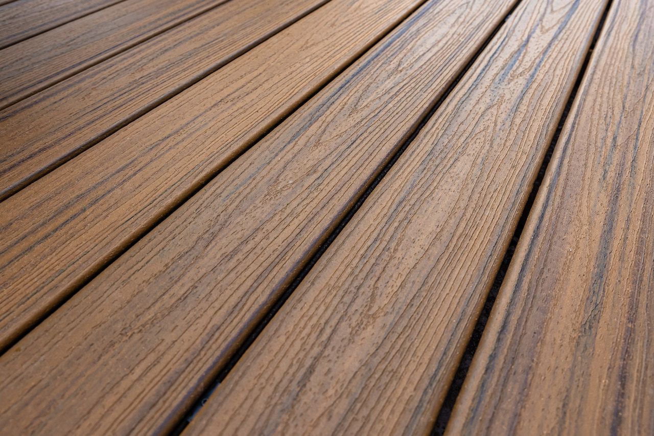 Gros plan sur des lames de terrasse composites brunes à texture de grain de bois.