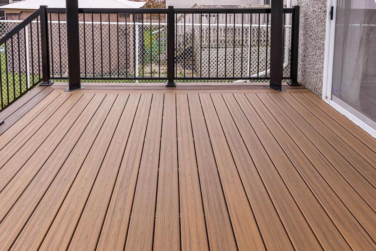 Terrasse en bois avec rambarde foncée. Des planches brunes s'étendent vers l'objectif.