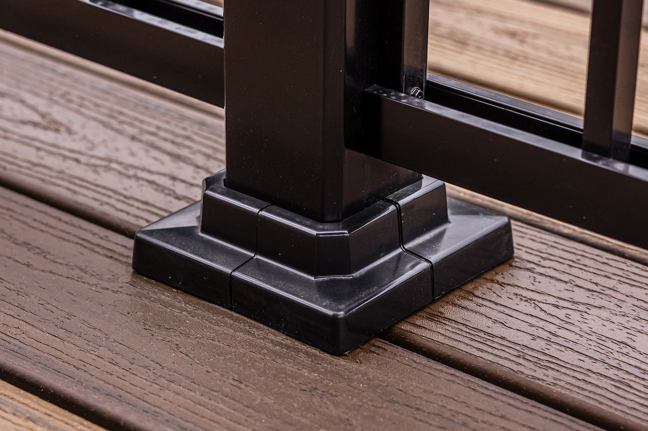 Poteau de rambarde noir avec base décorative sur une terrasse en bois.