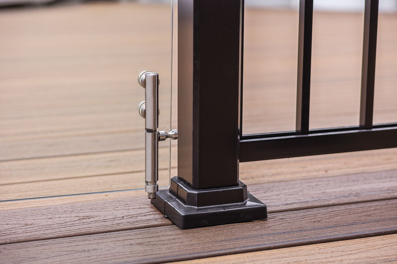 Gros plan sur un poteau de terrasse noir avec un système de garde-corps en câble métallique, fixé à une terrasse composite marron.