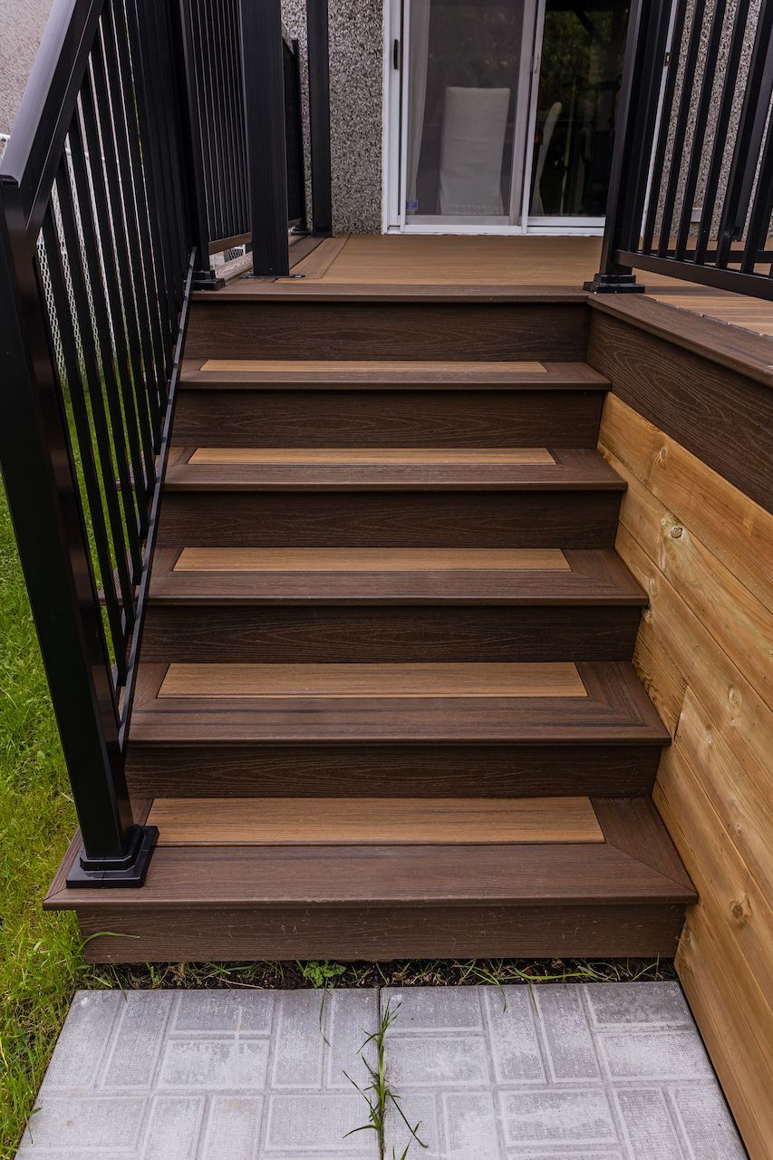 Escalier en bois avec marches brun foncé et accents brun clair, menant à une porte.