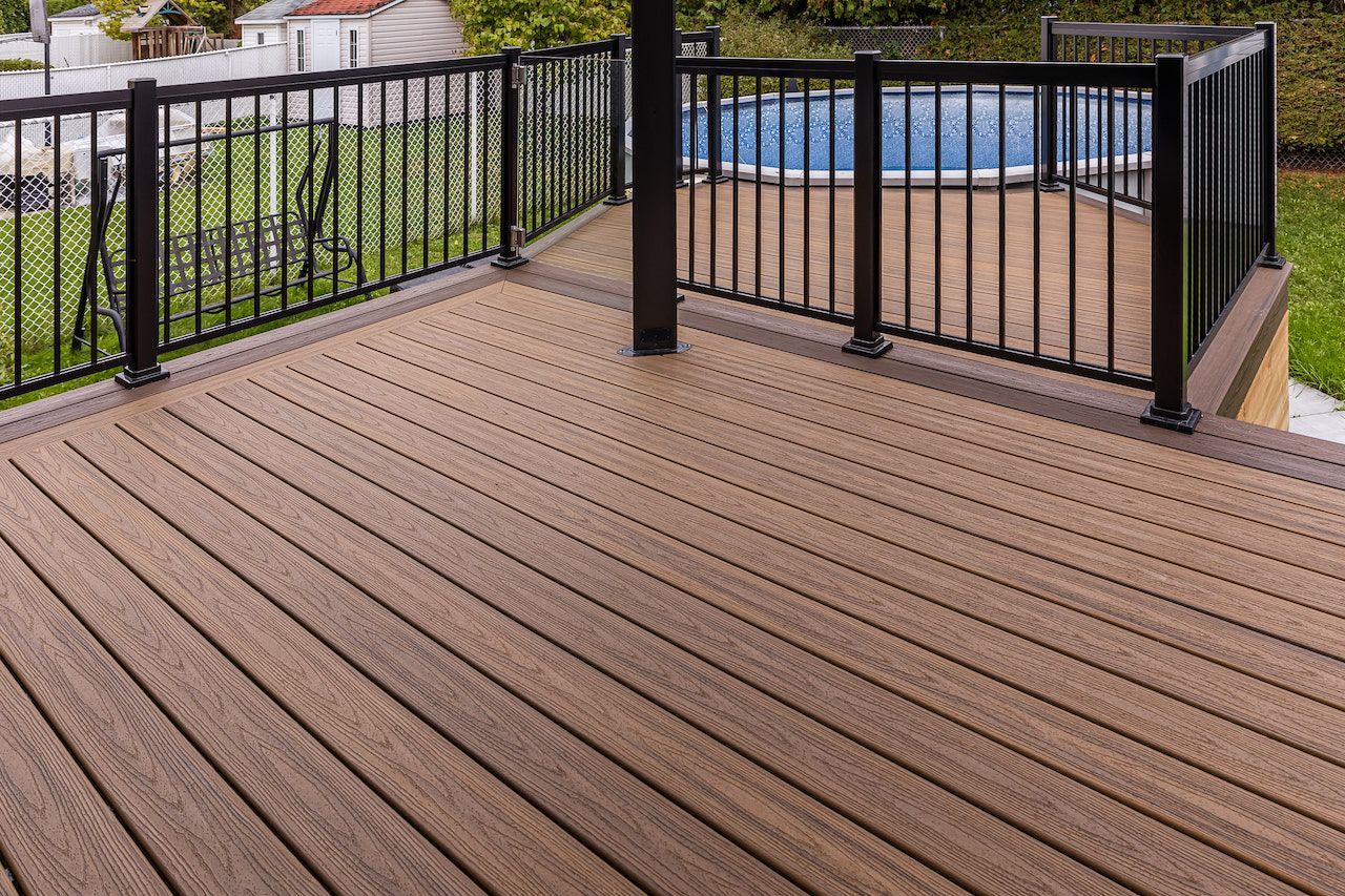Terrasse en bois avec rambardes noires entourant une petite piscine, vue d'en haut.
