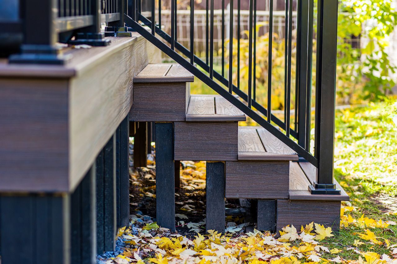 Escalier de terrasse en composite marron avec rampe noire, extérieur.