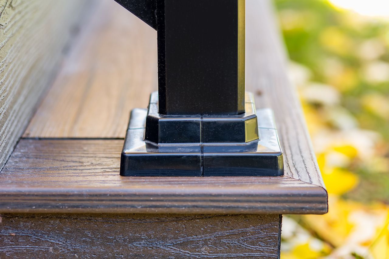 Poteau de terrasse noir sur une terrasse composite brune, avec une base carrée décorative.