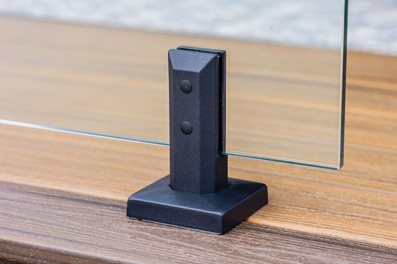 Pince en verre noir fixée sur une surface en bois, maintenant un panneau de verre.