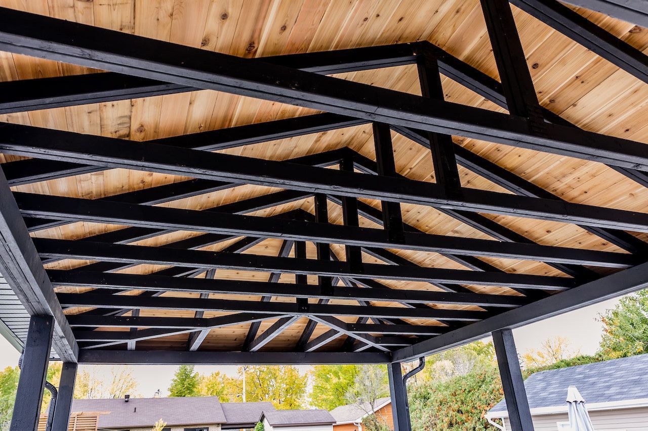 Toiture à ossature métallique noire avec planches de bois, à l'extérieur.