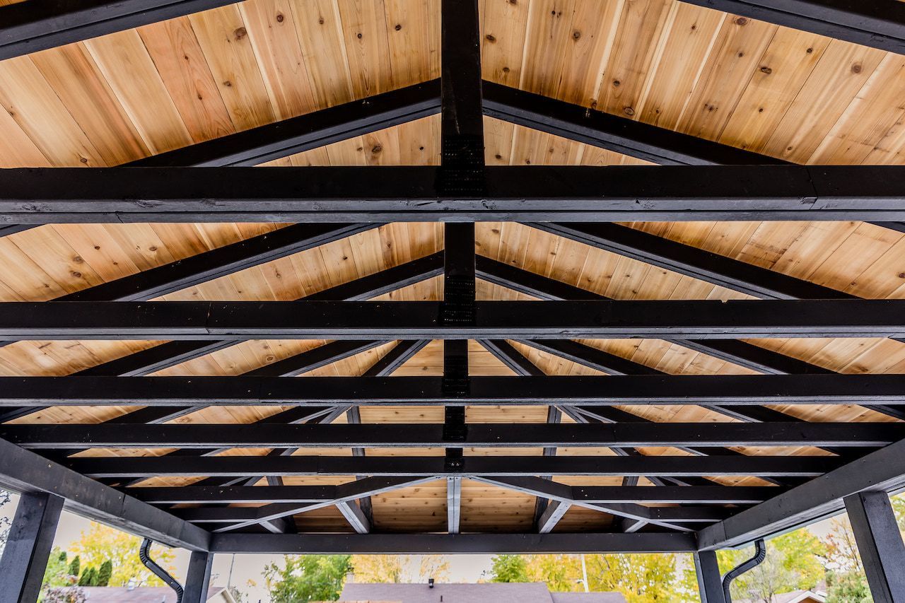 Plafond de gazebo en bois avec poutres noires et planches de cèdre.