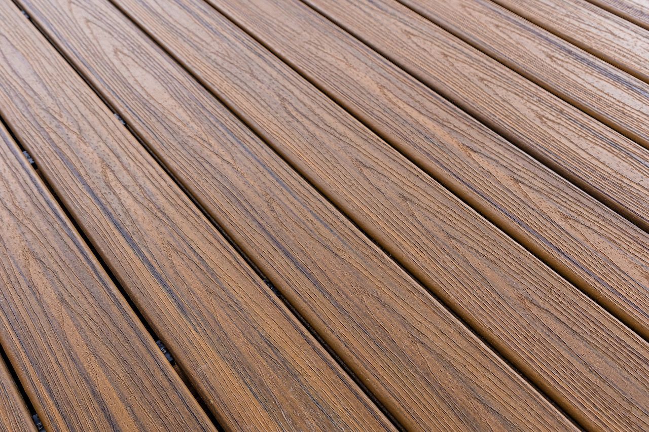 Planches de terrasse en bois, brunes avec un grain apparent, disposées en diagonale sur le cadre.
