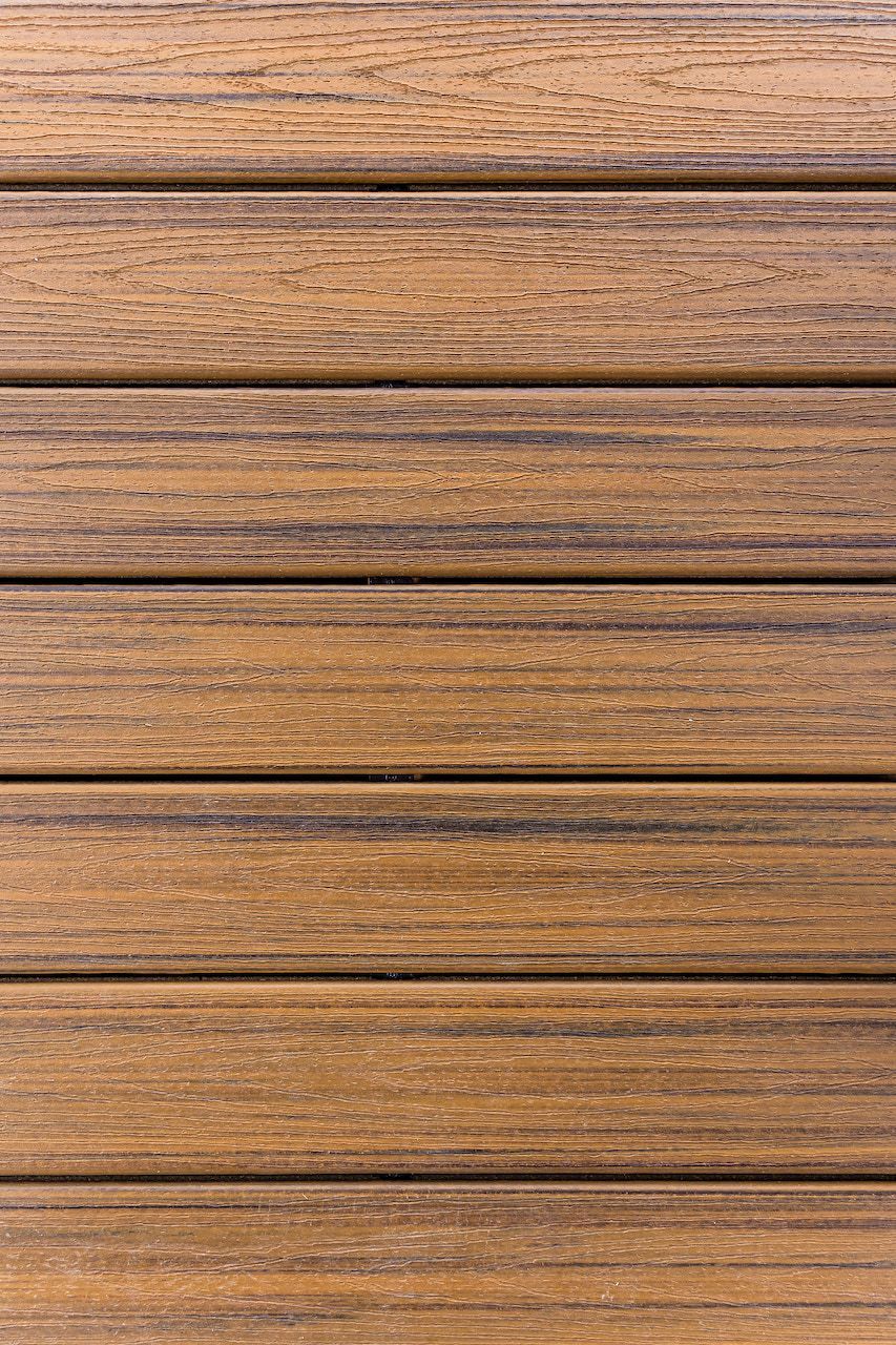 Lames de terrasse composites texturées brunes, pose horizontale, aspect bois clair.