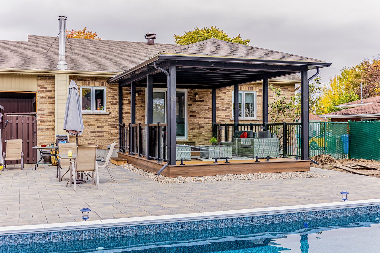 Terrasse arrière avec une pergola sombre, une maison en briques et une piscine.