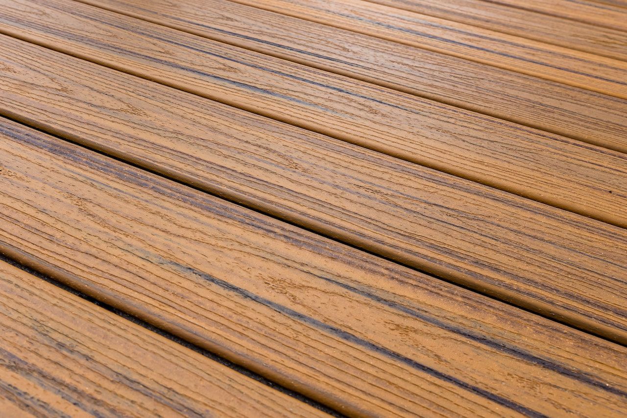 Gros plan sur des planches de bois, disposées en biais. Brun clair avec des lignes foncées entre les planches.