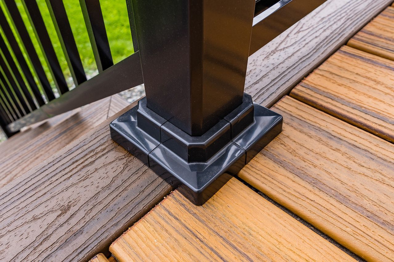 Poteau de terrasse noir avec base décorative sur terrasse en composite marron.