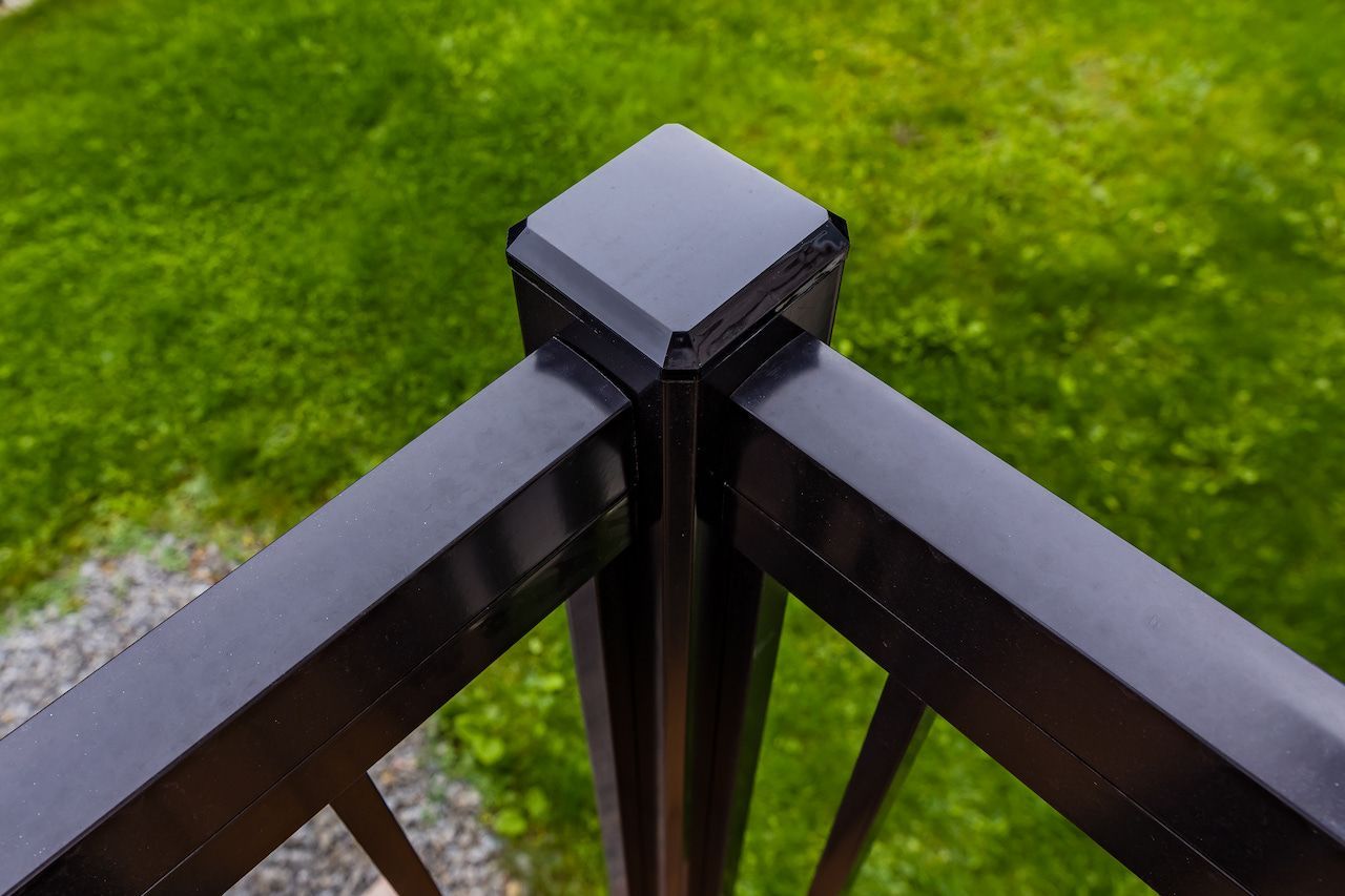Coin de rambarde de terrasse noire avec capuchon sur fond d'herbe verte.