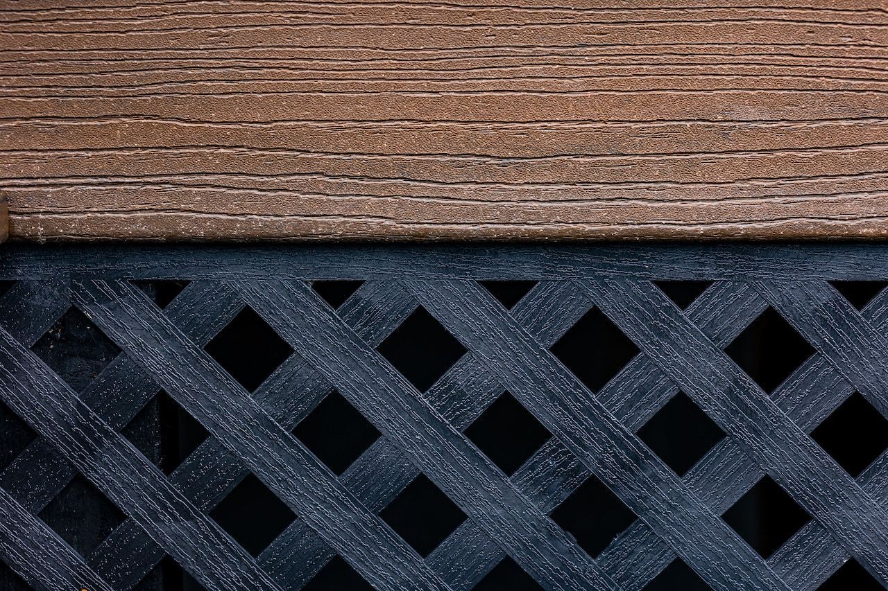 Planche de bois brun sur un treillis en losanges bleu foncé.