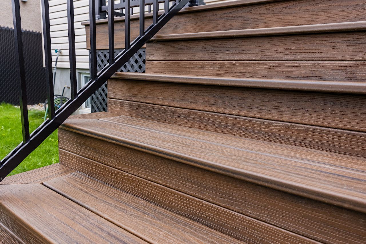 Escalier de terrasse en composite marron avec rampe noire, extérieur.