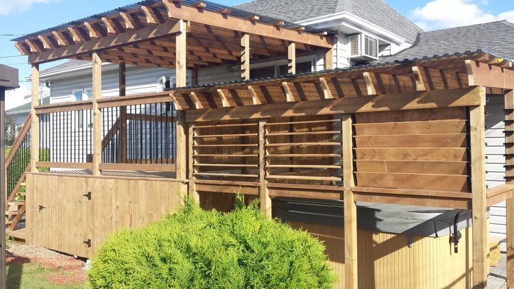 Terrasse en bois avec pergola, lattes et haie devant une maison.