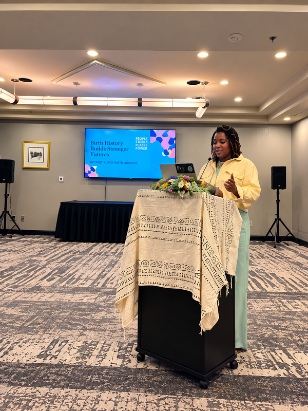 Shekita Long speaking at the 2025 Equity in Bloom Summit in Detroit. Shekita Long, CCHW, CBE speaking at the Equity in Bloom Summit at the Atheneum Hotel in Detroit, September 18–21, 2025, presenting from a podium during a conference session.
