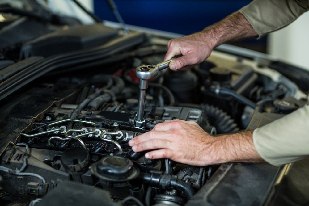 Mechanic using a wrench to work on a car engine.