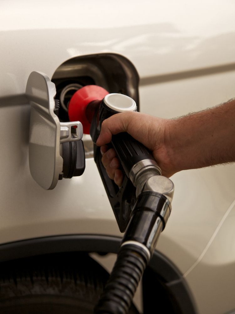 Hand pumping gas into a car at a gas station.
