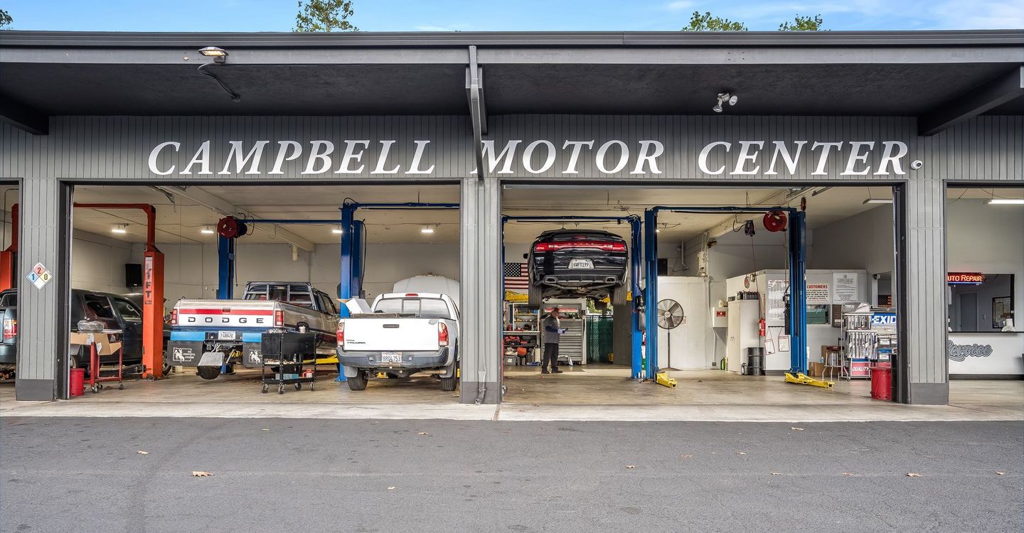 Campbell Motor Center garage with cars on lifts, workers, and tools.