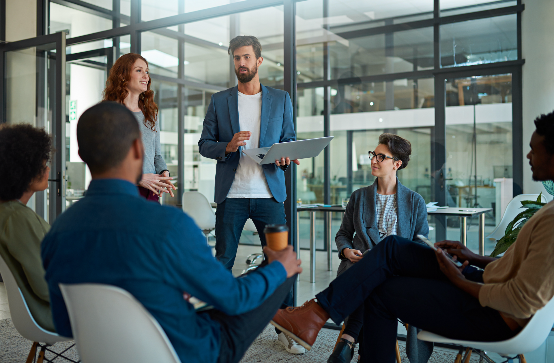 A group of people are sitting in a circle in an office having a meeting.