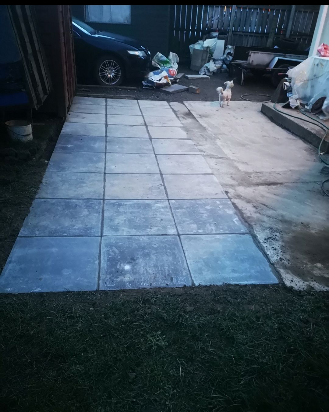 Paved walkway made of square concrete slabs in backyard.