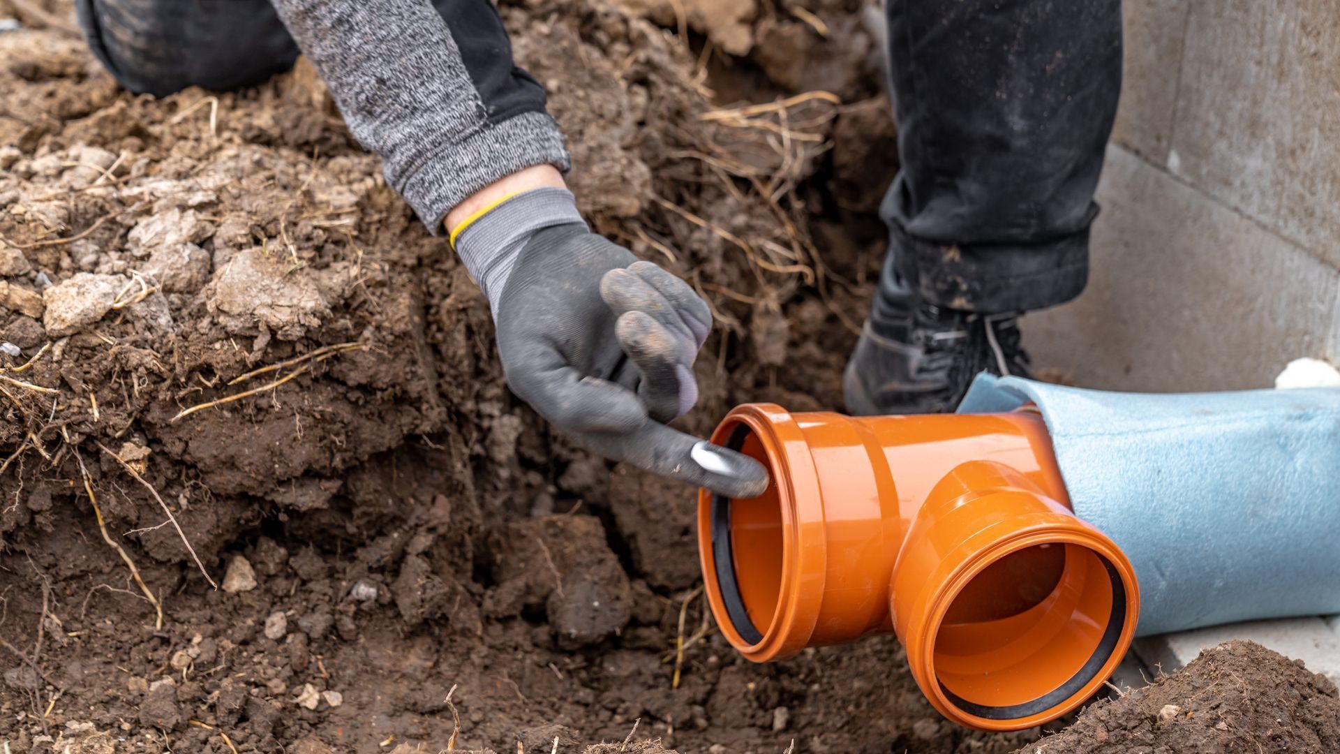 A man is installing a drain pipe in the ground.