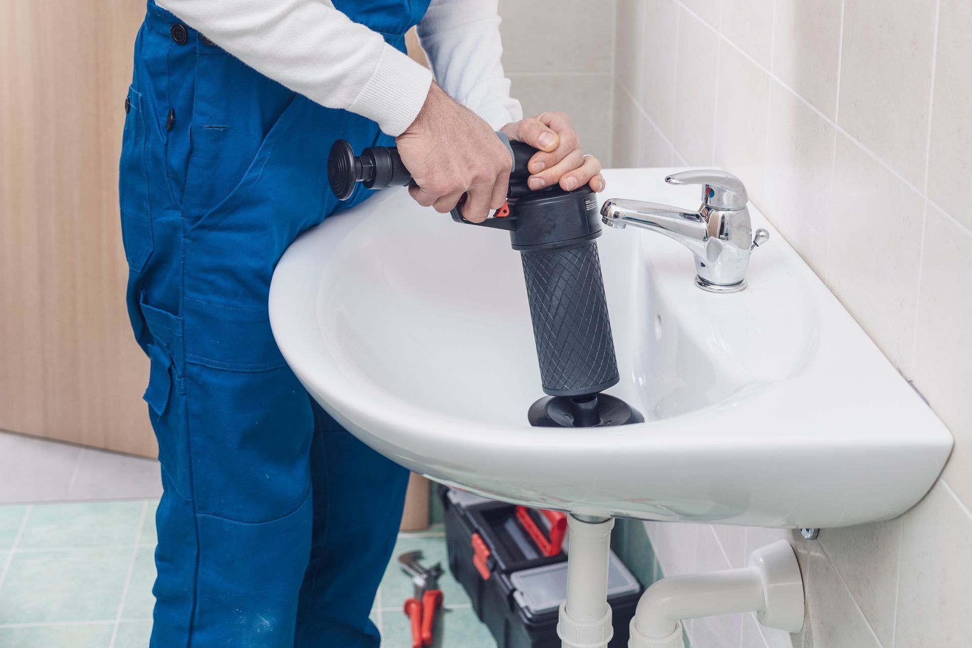 A plumber is using a plunger to unblock a sink.