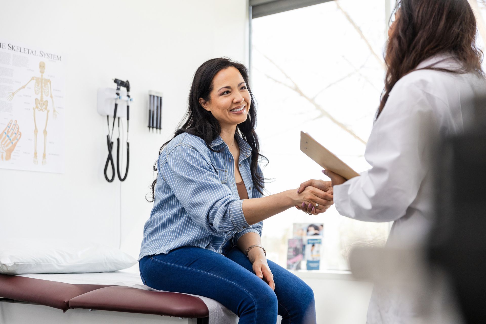 A woman is sitting on a bed shaking hands with a doctor. A woman is sitting on a bed shaking hands with a doctor.