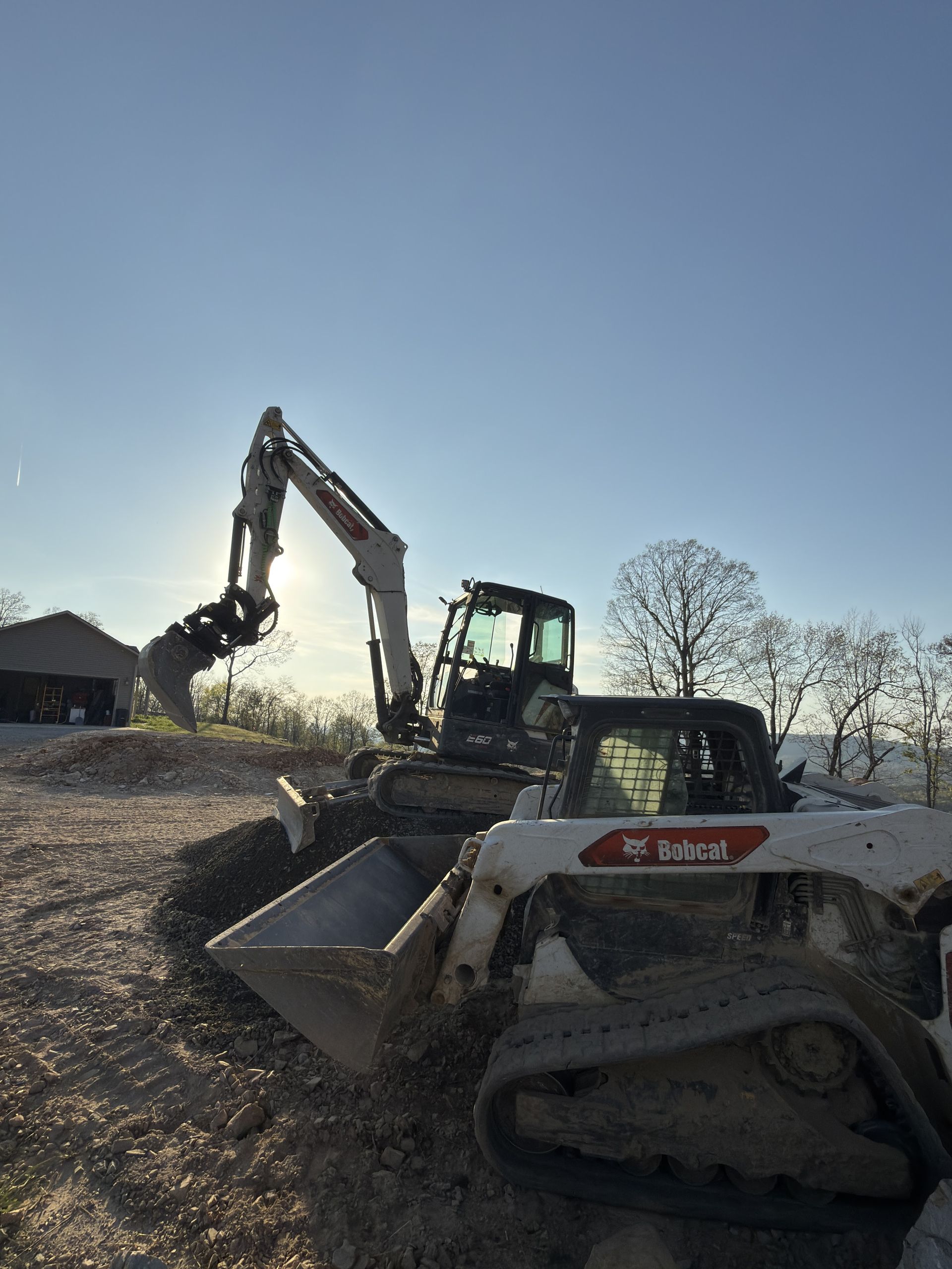 Excavator loading rubble into a dump truck at a construction site under a bright sky