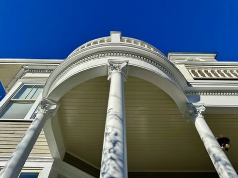 Three white pillars holding up a balcony