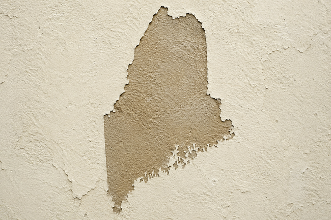 A wall with peeled paint in the shape of Maine